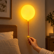 Hand operating the pull cord on a wall-mounted balloon night light